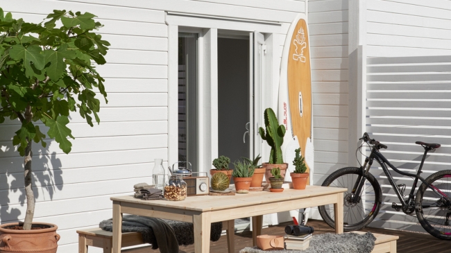 Ett hus med vit träfasad, samt utemöbler och växter