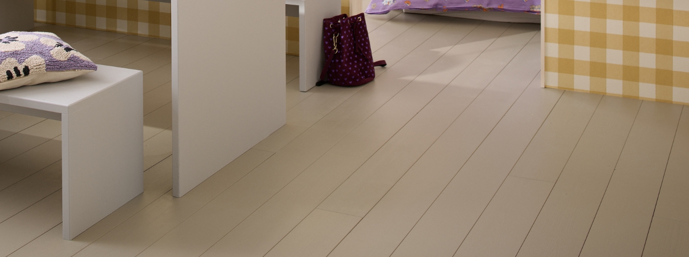 Sovrum med beigemålat furugolv, väggar med gul- och vitrandig tapet, en säng och ett vitt bord med två vita bänkar