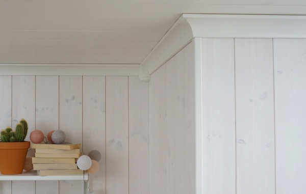 Taklister och vägg med panel, samt en hylla med kruka