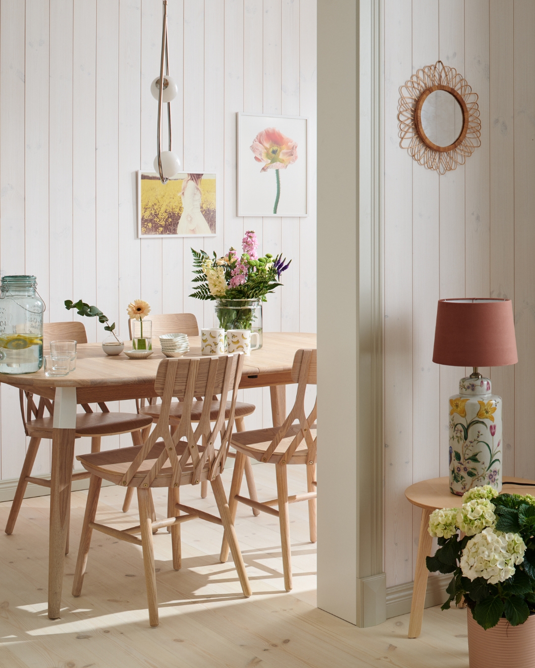 Bord och stolar i trä, en vit panel, beiga lister och trägolv
