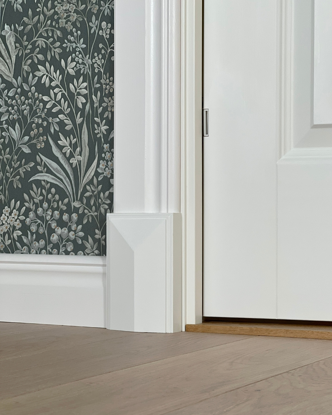 Vita lister, golvkloss och en grön tapet med mönster