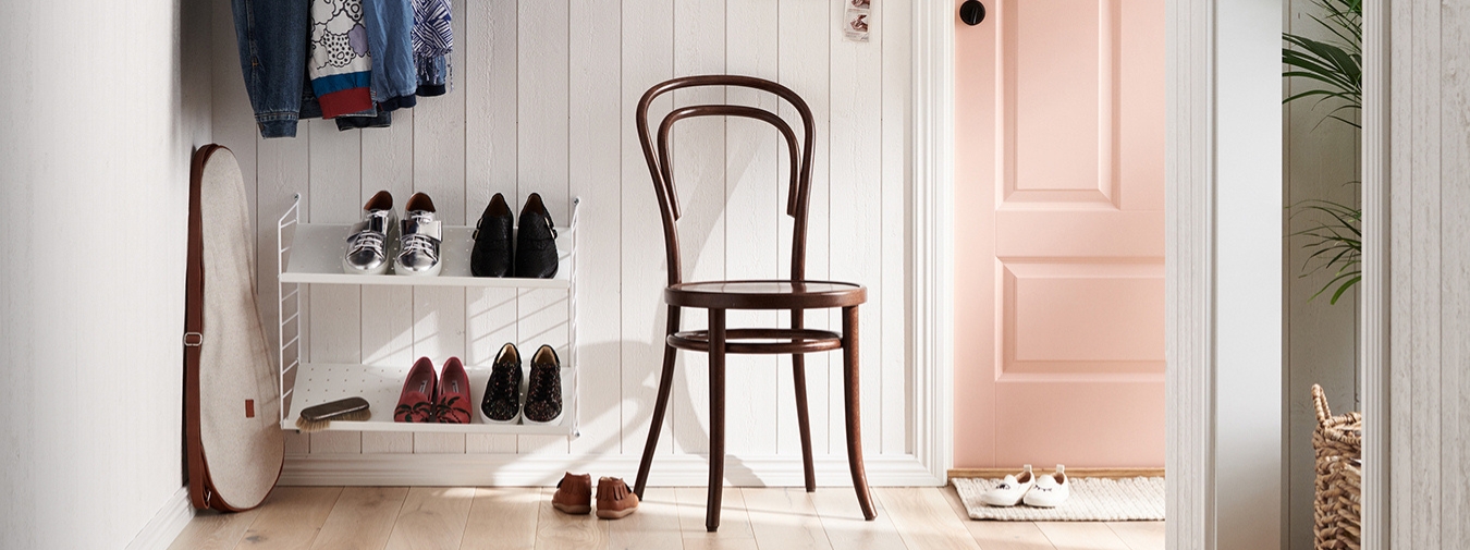 Vardagsrum med trägolv och vit träpanel. Soffa, soffbord, fåtölj, byrå och piedestal. Samt blommor och andra detaljer