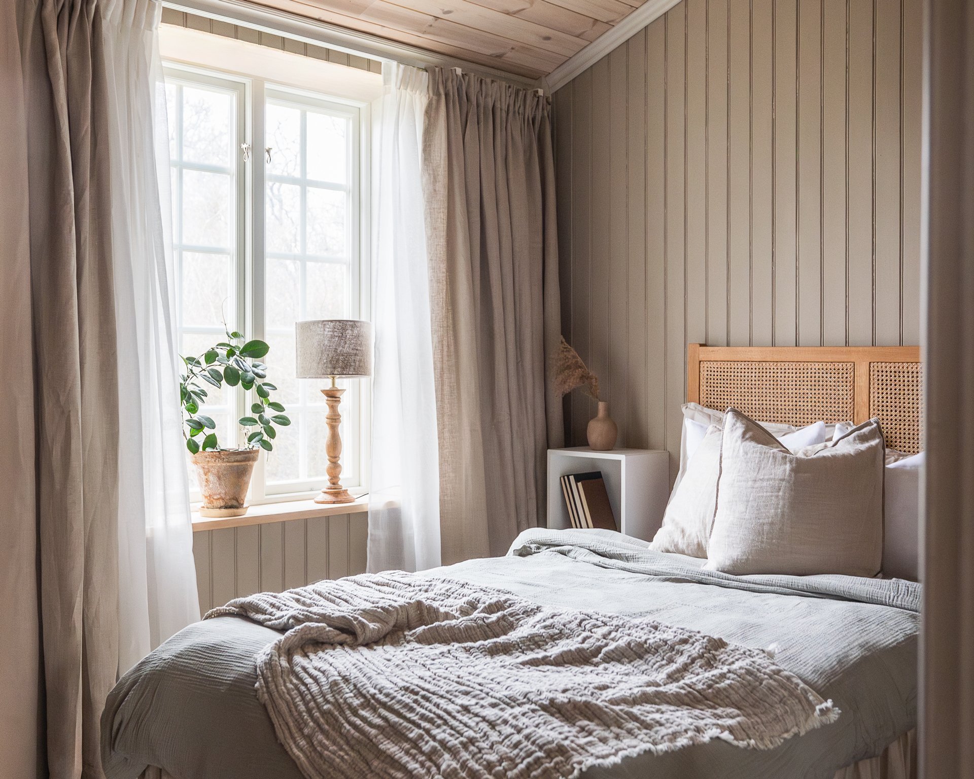 Sovrum, fönster och en träpanel i beige pärlspont