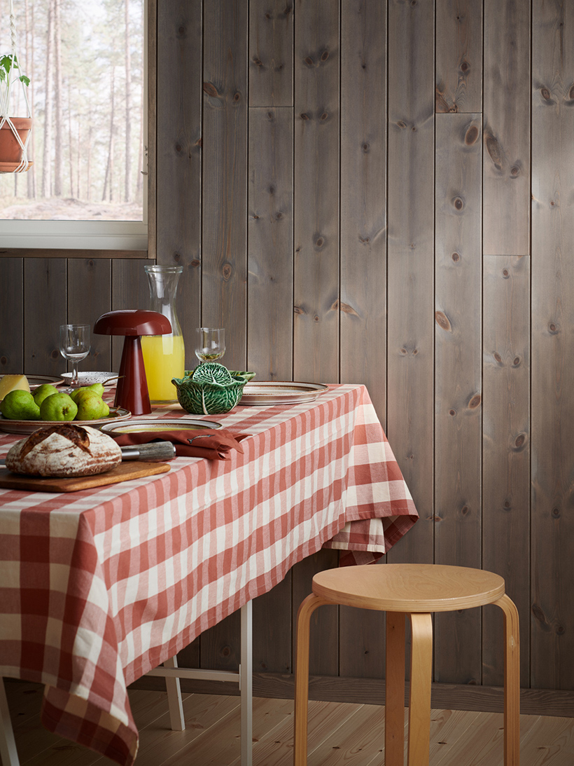 Träpanelen Stilla Gärdsgårdsgrå på väggen. Ett bord med rutig duk är dukat.