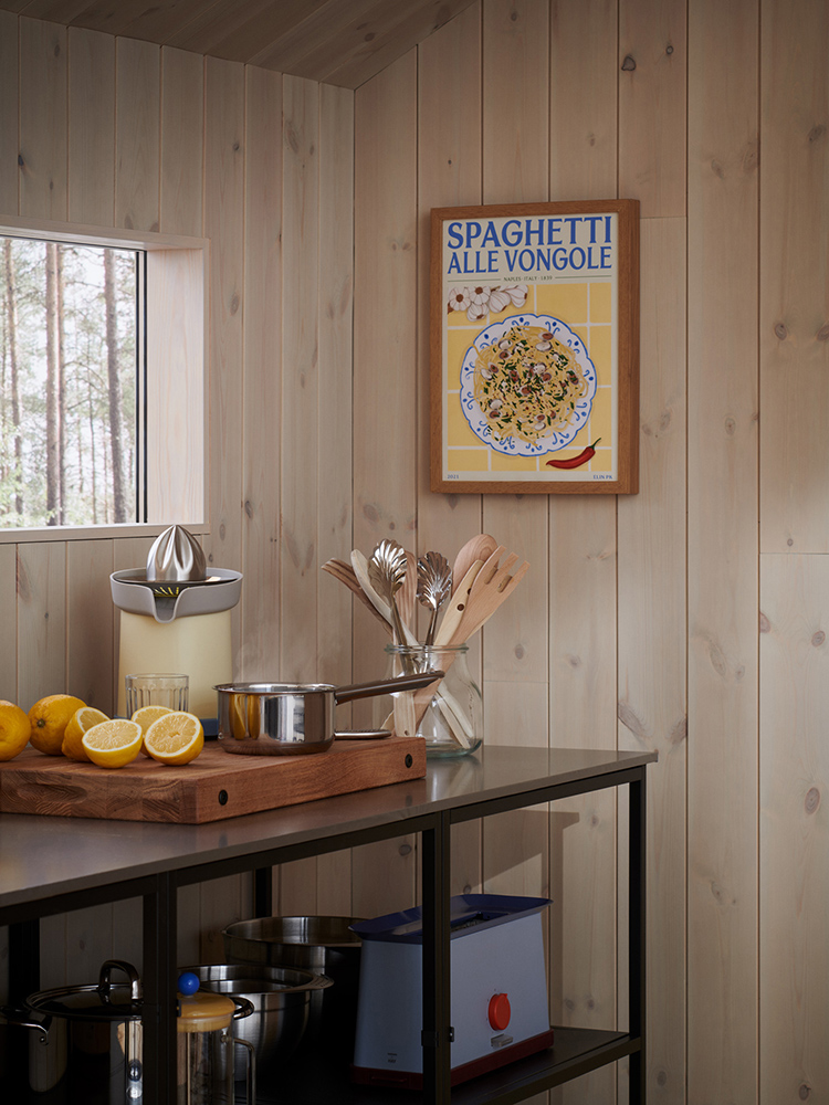 Träpanelen Stilla Morgondis sitter på väggarna och i taket i ett kök. Ett liggande fönster till vänster med utsikt mot en tallskog.