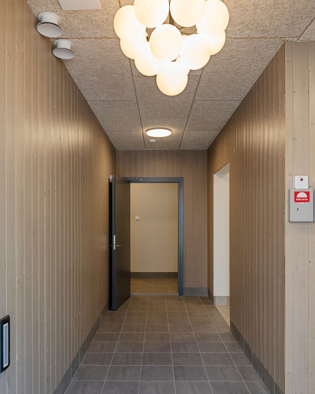 Entré i trapphus med träpanel på väggarna, lampa i taket