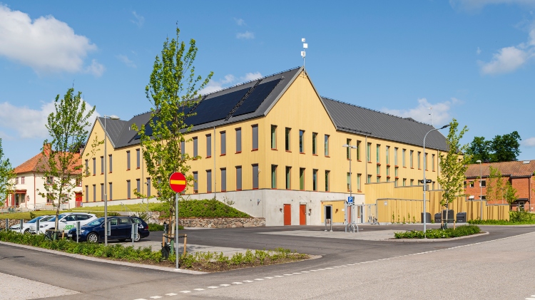 Parkering framför Östra Göinge kommunhus med fasad av ThermoWood BT Pigment Ockragul