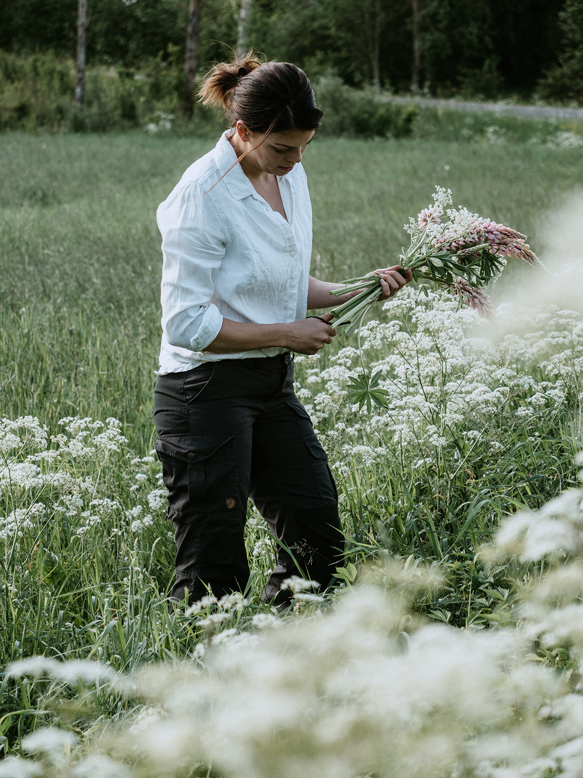 Johanna i vit skjorta plockar blommor på ängen