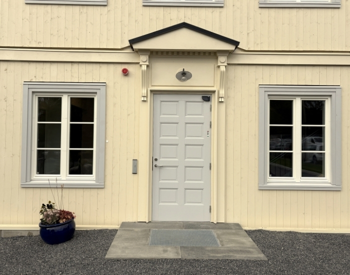 Inngangsparti til Blindern STudenterhjems nye nordfløy med trekledning i gult, lysegrå innramming av vinduene og en lyse grå inngangsdør