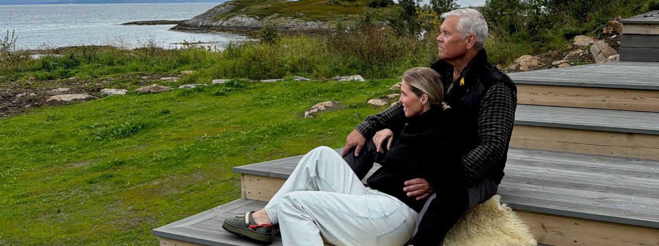 Hege og Jan Roger sitter sammen på terrassen ved Haveng, med havet og naturen på Rolløya i bakgrunnen.