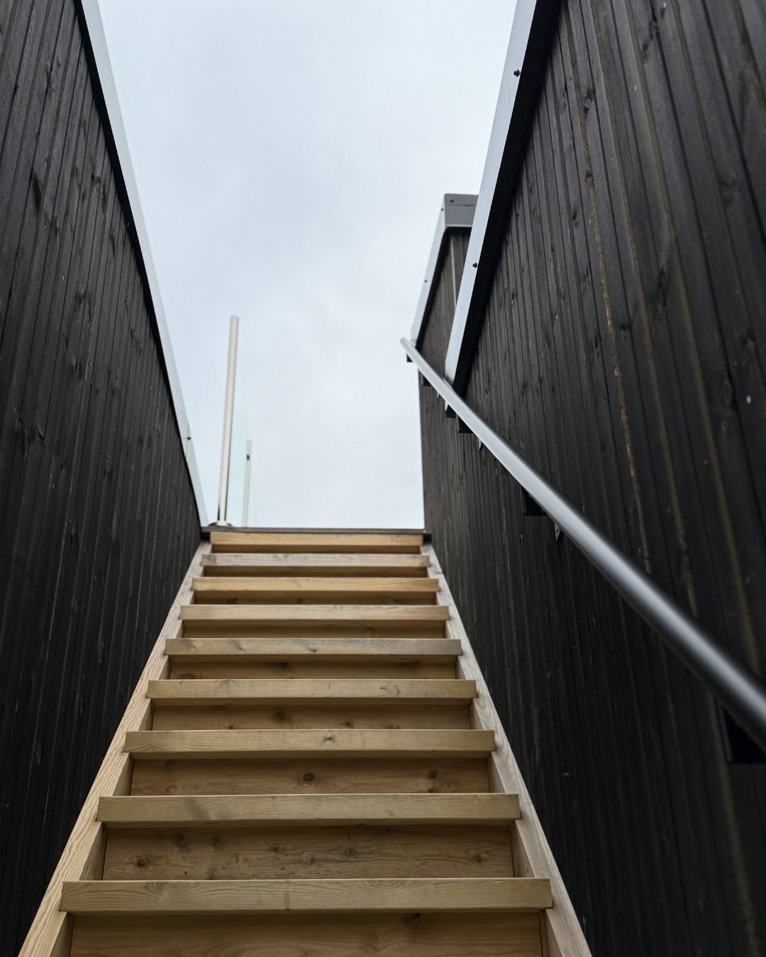 Utvendig tretrapp mellom to vegger med mørk trekledning på Haveng.