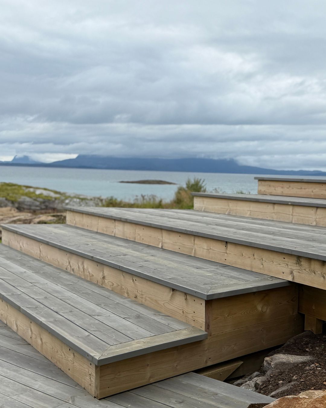 Brede tretrinn i terrassen danner et lite amfi med utsikt mot havet og fjellene.