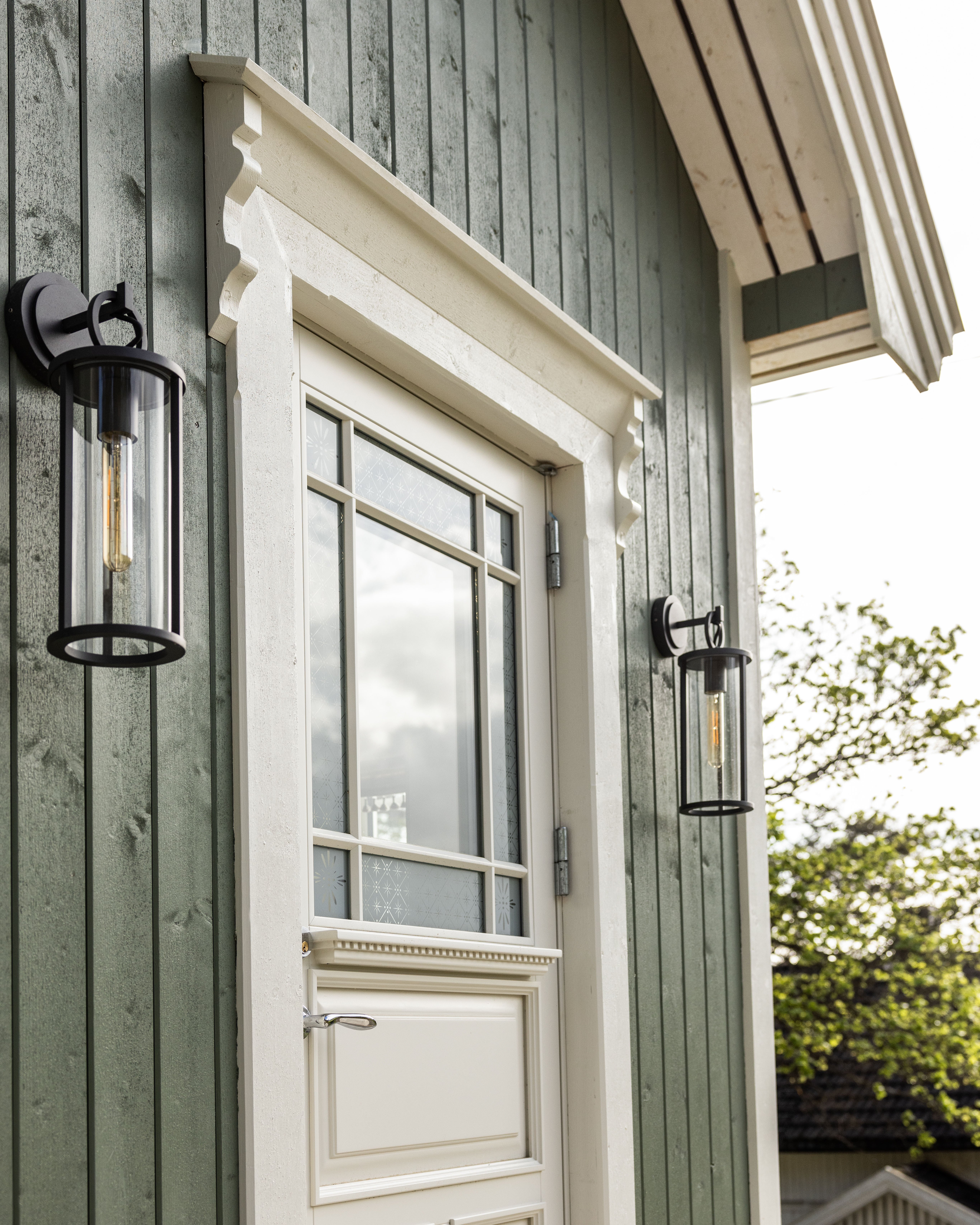 Inngangsdøren til det lille huset malt i grønnfargen Stockholmsgrønn og staffasje i Tidløs