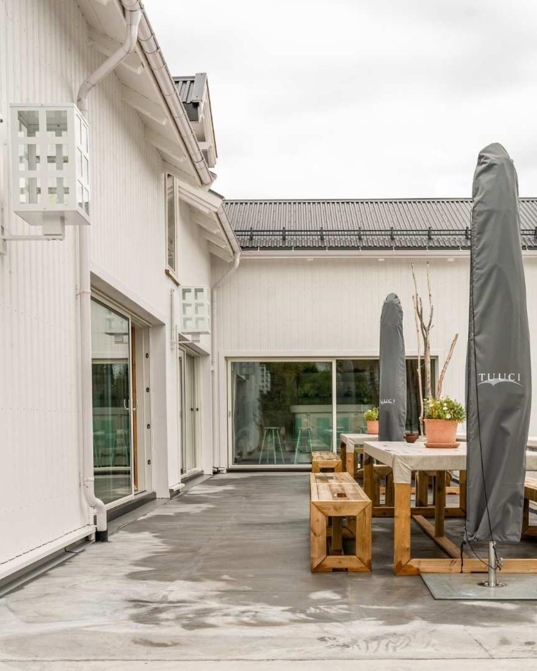Innebygd terrasseareal ved Villa Oslofjord med hvit trekledning, store glassdører og trebenkesett under en lukket parasoll.