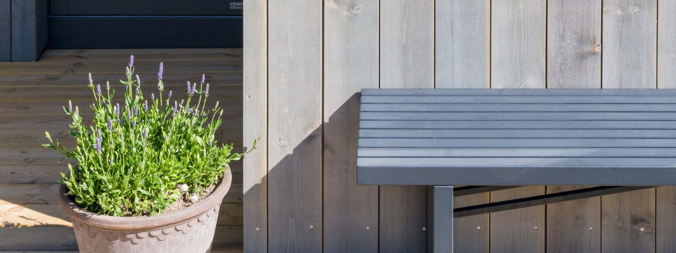 Værbitt Gråna kledning med benk og blomster