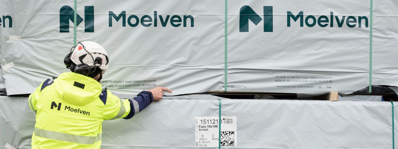 Arbeider foran pakker med trelast fra Moelven, klare for levering til byggeplass.