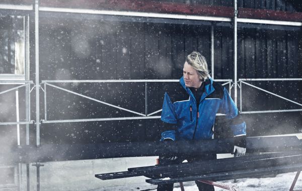 Heftig kledning fra Moelven, som blir montert i snøvær av en mann i blå kjeledress