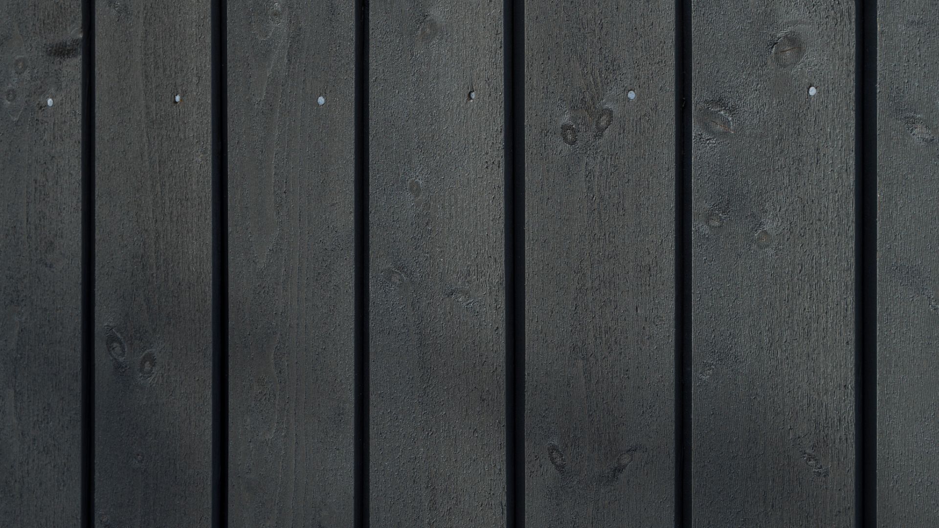 Nærbilde av Heftig Pro i fargen Labrador. Synlige kvisthull og spikerhoder viser trevirketes naturlige karakter under den mørke overflatebehandlingen.