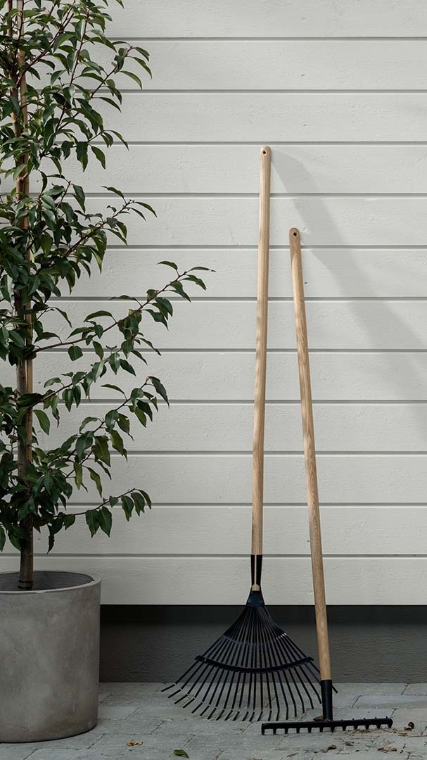 Klednigsvegg i fargen Dus med hageredskaper lent til veggen.