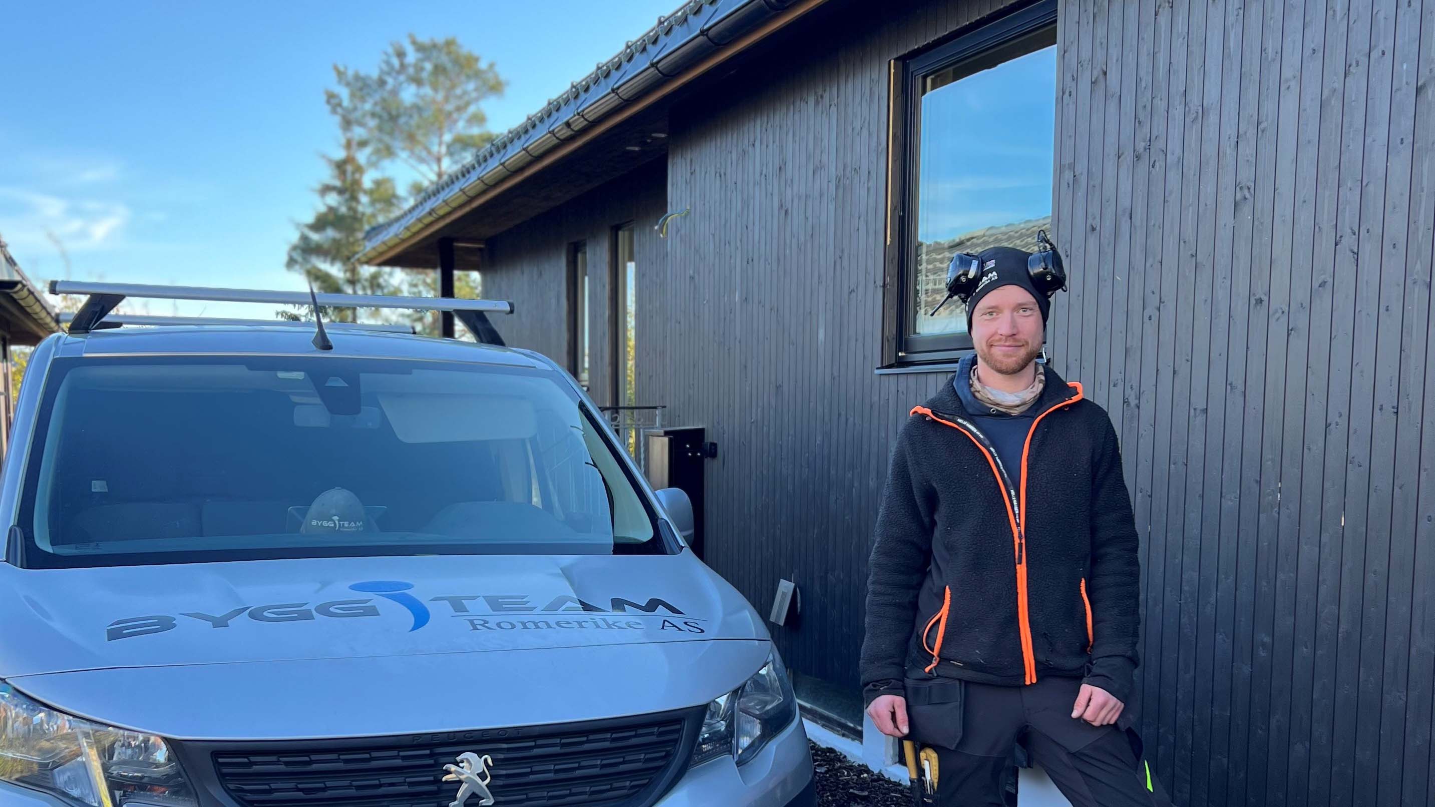 Snekker foran huset han holder på å kle med Heftig Pro+ med skjult innfesting