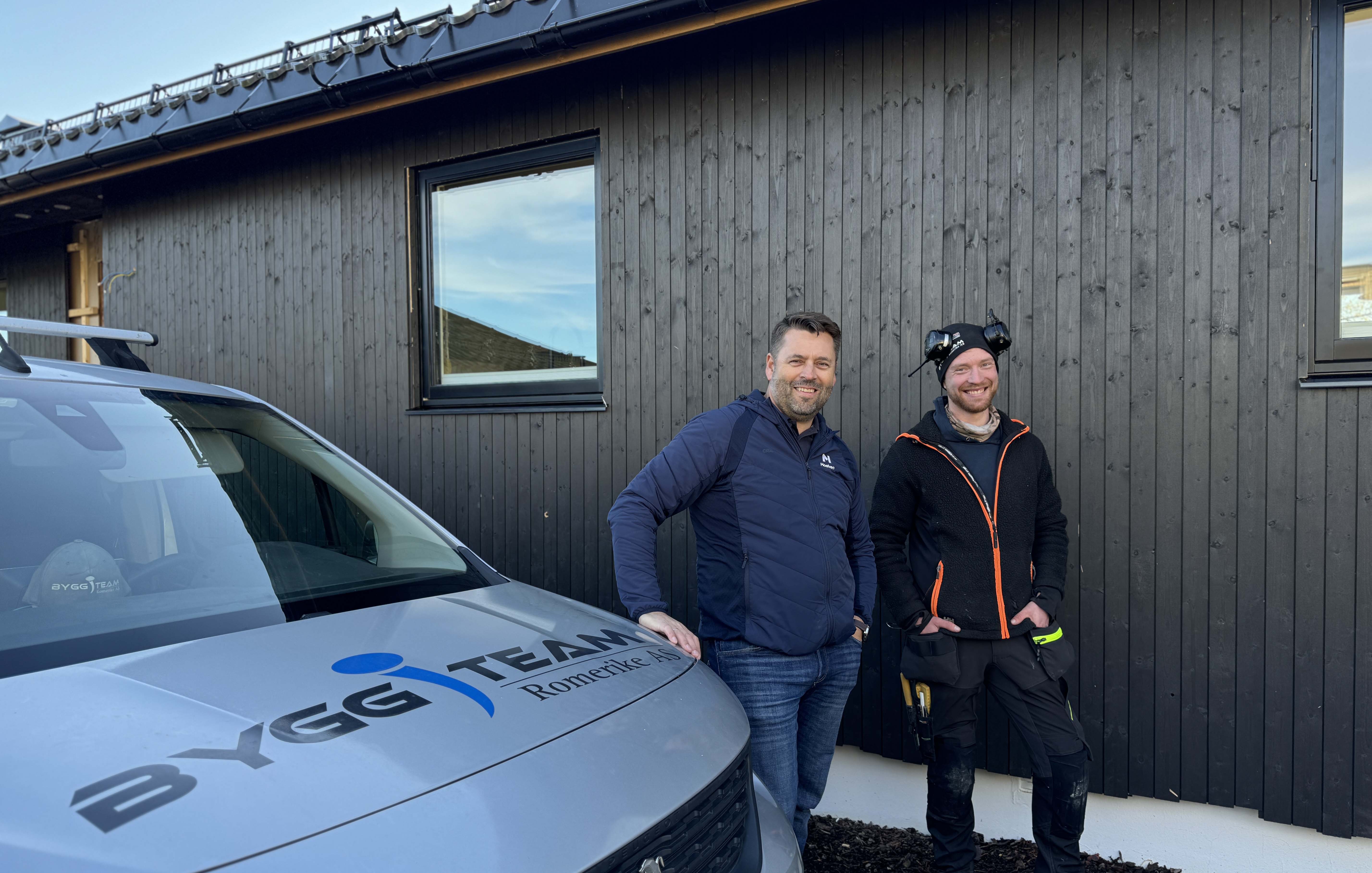 Snekker og Moelven representant foran hus som er i ferd med å få ny Heftig kledning med skjult innfesting