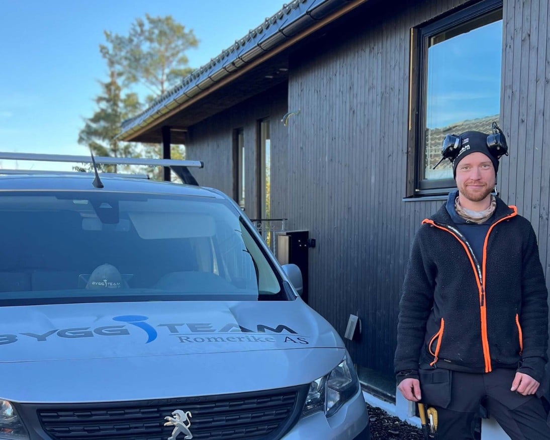Tømrer Fredrik fra Byggteam Romerike foran bilen sin og huset med Heftig PRO+ Null Hull kledning med skjult innfesting