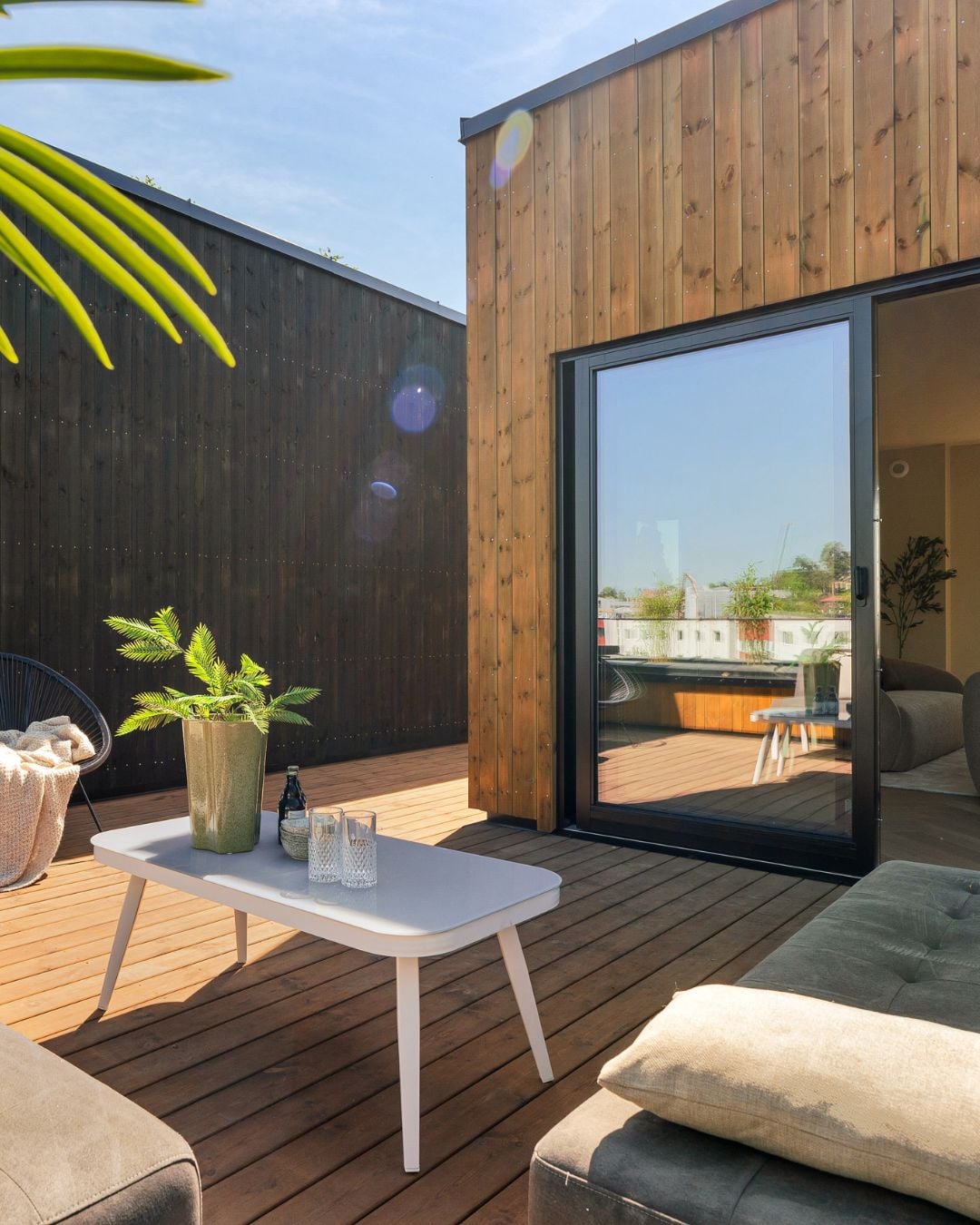 Solrik terrasse mellom boliger med stående Værbitt kledning i fargene Garva og Fura.