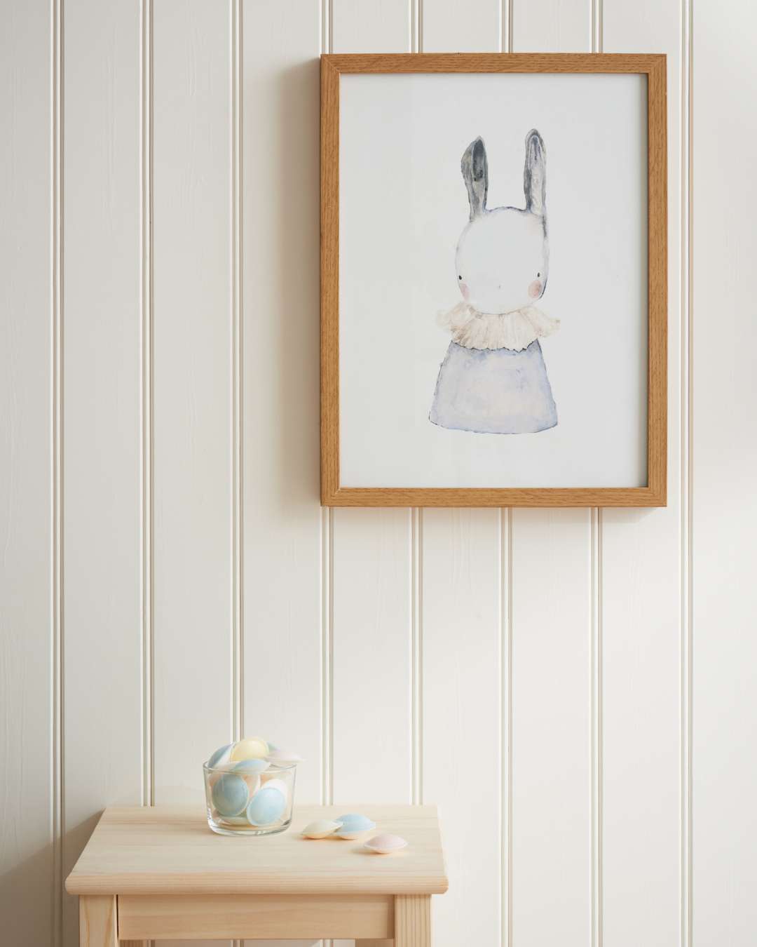 Trepanel i perlestaff malt hvit med bilde og et lite bord